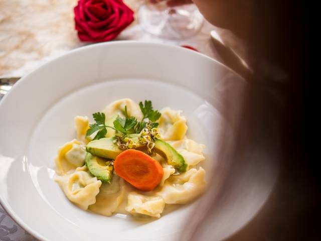Pasta-Teller mit Gemüse, Karotte und Petersilie, serviert mit Rotwein und Rosen-Dekoration