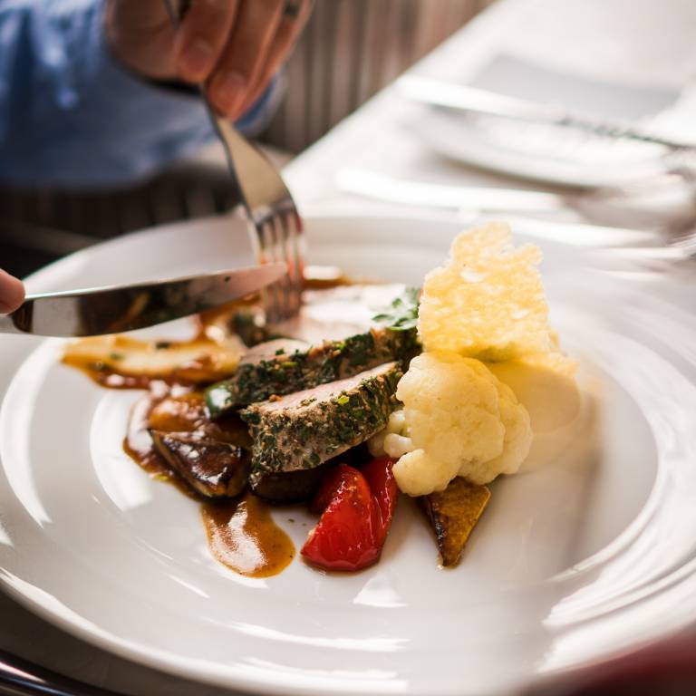 Hauptgericht mit Fleisch, Paprika, Blumenkohl und Sauce auf elegant angerichtetem Teller